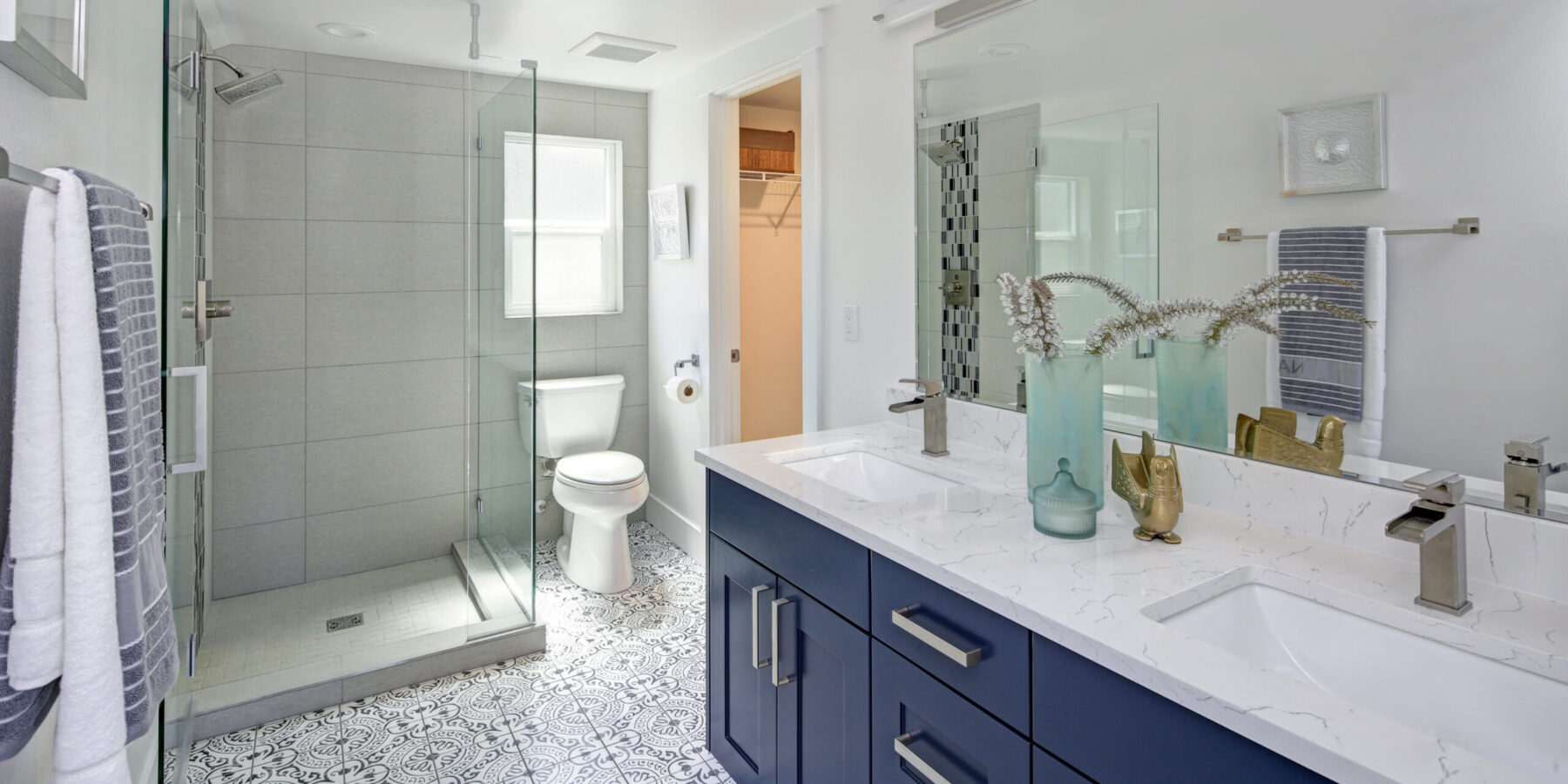 Modern bathroom interior with blue double vanity and glass shower.